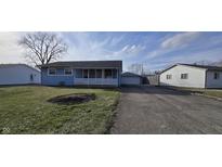 Charming one-story home with blue siding, a well-kept lawn and a long driveway at 809 Carlin Dr, Shelbyville, IN 46176