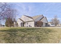 Tan two-story house with a grassy lawn, attached garage, and driveway at 1196 Brittany Cir, Brownsburg, IN 46112