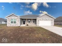 Ranch style home with gray siding, stone accents, and a two-car garage at 20 Lancaster Ct, Trafalgar, IN 46181
