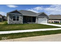Charming single-story home features stone accents, manicured lawn, and attached two car garage at 20 Lancaster Ct, Trafalgar, IN 46181
