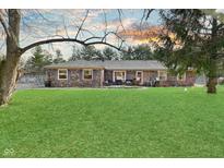 Expansive backyard featuring a well-maintained lawn and a charming brick house at sunset at 3301 Timberbrook Ct, Danville, IN 46122
