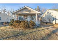 Beige bungalow with front porch, landscaping, and a spacious yard at 4512 East 21St St, Indianapolis, IN 46218