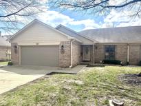 Charming brick home with an attached garage and well-manicured lawn under a partly cloudy sky at 5299 Carnoustie Cir, Avon, IN 46123