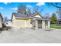 Charming yellow home featuring a spacious driveway and quaint, decorative front porch at 4632 Normal Ave, Indianapolis, IN 46226