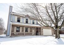 Charming two-story home featuring a cozy front porch and an attached garage, set in a snowy landscape at 12643 Feldspar Rd, Indianapolis, IN 46236