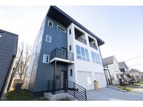 Modern three-story home with dark blue and white exterior, two-car garage, and a balcony at 1523 Marlowe Ave, Indianapolis, IN 46201
