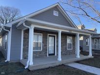 Charming home features stone accents, stylish gray siding, and a welcoming covered front porch at 2426 S Holt S Rd, Indianapolis, IN 46241