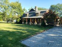 Lovely home with a covered porch, lush green lawn, mature trees, and a stone driveway, creating a picturesque setting at 1307 W 161St St, Westfield, IN 46074