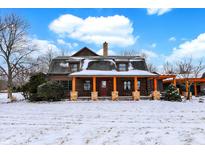 Charming log home featuring orange accents on the porch in a snow-covered setting at 1307 W 161St St, Westfield, IN 46074