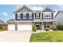Charming two-story home with blue siding, brick accents, a well-manicured lawn and a three car garage at 1324 Trailside Dr, Greenwood, IN 46143