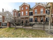 View of brick townhomes with black iron fence, signage, and budding trees in a landscaped lawn area at 6617 Reserve Dr, Indianapolis, IN 46220