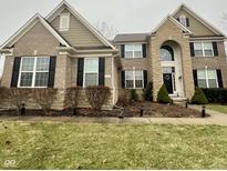 Charming two-story home featuring a brick and stone facade, black shutters, and manicured landscaping at 2504 Fawn Bluff Ct, Zionsville, IN 46077