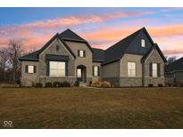 Stunning two-story brick home featuring a well-manicured lawn and a charming architectural design at sunset at 5106 Zinnia Dr, Plainfield, IN 46168