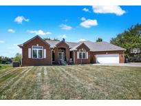 Brick ranch home with attached garage, landscaping, and basketball hoop at 746 N Buck Creek Rd, Greenfield, IN 46140