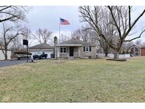 Charming single-story home with a detached garage, American flag, and partially-wooded yard at 110 Tulip Dr, Indianapolis, IN 46227