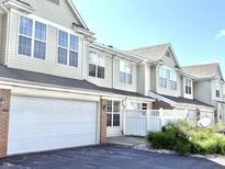 Inviting townhouse showcasing attached garage, neutral siding, and well-maintained landscaping at 2231 Colfax Ln, Indianapolis, IN 46260