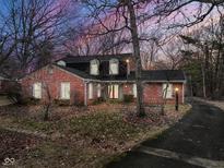Charming red brick home with a well-maintained lawn and mature trees during twilight at 4020 E 71St St, Indianapolis, IN 46220