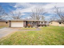 Charming brick home featuring an attached garage and well-maintained front yard with mature trees and a welcoming entrance at 511 Fall Creek Dr, Anderson, IN 46013