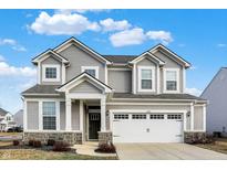 Two-story house with gray siding, white garage doors, and landscaping at 6562 Overlander Ln, Whitestown, IN 46075