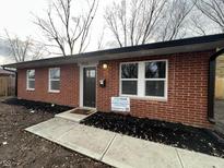 Charming brick home featuring updated windows, fresh landscaping, and a welcoming entrance at 3926 Downes Dr, Indianapolis, IN 46235