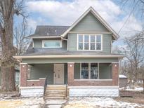 Charming two-story home features a covered porch, brick accents, and eye-catching window design at 5511 E University Ave, Indianapolis, IN 46219