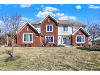 Charming two-story home featuring a red brick and white facade, set against a bright blue sky at 1845 Knaphill Ct, Carmel, IN 46033