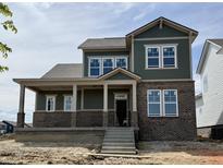 Two-story home with green siding, brick accents, covered porch, and multiple windows at 19997 Old Dock Rd, Westfield, IN 46074