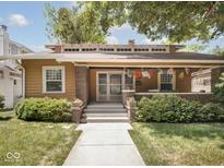 Charming bungalow with a welcoming front porch, brick accents, and colorful prayer flags at 4220 Sunset Ave, Indianapolis, IN 46208