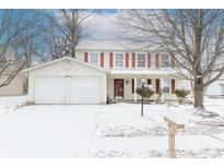 Two-story home featuring a two-car garage, red shutters and a snow-covered yard at 12644 Spurrington Way, Indianapolis, IN 46236
