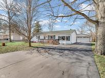 Inviting home showcasing an extended driveway, detached garage, lovely front porch, and well-maintained landscaping at 216 Suburban St, Danville, IN 46122