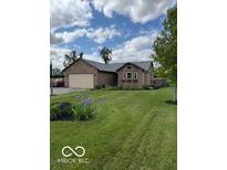 Charming brick home with attached garage and well-maintained front lawn and garden at 2650 W State Road 252, Flat Rock, IN 47234