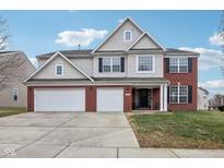 Charming two-story home featuring a three-car garage, landscaped yard, and a mix of brick and siding at 13023 Ambergate Dr, Fishers, IN 46037
