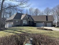 Beautifully landscaped front yard with a traditional-style brick home and a circular driveway leading to the garage at 13221 Barnegat Ln, Fishers, IN 46055