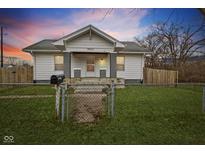 Charming home featuring a well-maintained lawn, fenced yard, and inviting front porch at 3950 W Michigan St, Indianapolis, IN 46222