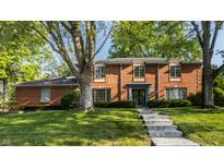 Stately brick home featuring mature trees, manicured lawn, and inviting stone walkway at 1210 Chessington Rd, Indianapolis, IN 46260