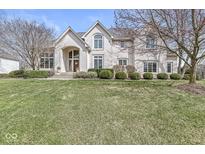 Beautifully landscaped two-story home with brick exterior, arched entryway and large windows at 13701 Cheswick Blvd, Carmel, IN 46032