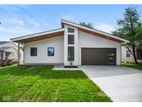 Modern home featuring a sleek design, dark garage door, striking windows, and a well-manicured lawn at 2689 Pearl St, Columbus, IN 47201
