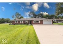 A charming single-story brick home with a well-manicured lawn and an extended driveway at 1002 Payton Ave, Indianapolis, IN 46219