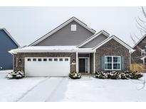 Charming single-story home featuring a brick facade, gray siding, a two-car garage and a snow-covered front yard at 1034 Long Stand Dr, Greenwood, IN 46143