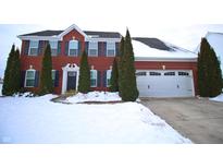 Charming red brick two-story home with a two car garage and evergreen trees in a snowy landscape at 1169 Richmond Ln, Greenwood, IN 46143