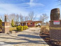 Paver driveway leads to charming red brick home with professional landscaping and decorative brick column at 2210 Louise St, Anderson, IN 46016