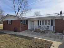 Charming single-story home with brick accents, metal roof, and a cozy front porch seating area at 4601 W Bradford Dr, Muncie, IN 47304