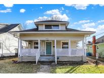 Charming home with a welcoming front porch, white railing, and a vibrant teal door, complemented by a well-kept lawn at 529 W 42Nd St, Indianapolis, IN 46208