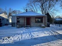 Charming single-story home featuring red door and stone accents, front lawn covered in snow at 603 W 33Rd St, Anderson, IN 46013