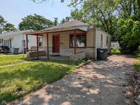 Cozy one-story home featuring a covered porch and mature trees surrounding the property at 603 W 33Rd St, Anderson, IN 46013