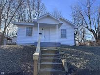 Charming home featuring a covered front porch and set of concrete stairs leading to the main level at 605 W 10Th St, Muncie, IN 47302
