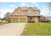 Charming two-story brick home featuring a well-manicured lawn, green shutters, and a two-car garage at 685 Greystone Ct, Columbus, IN 47201