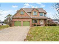 Charming brick home featuring a two-car garage, well-maintained lawn and distinctive green shutters at 685 Greystone Ct, Columbus, IN 47201