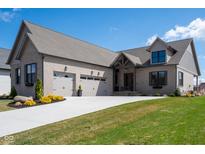 Beautiful gray brick home featuring an attached two-car garage and a well-manicured lawn and driveway at 16392 Grand Cypress Dr, Noblesville, IN 46060