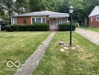 Charming single-story brick home featuring a well-manicured lawn and mature trees at 1925 N Leland Ave, Indianapolis, IN 46218